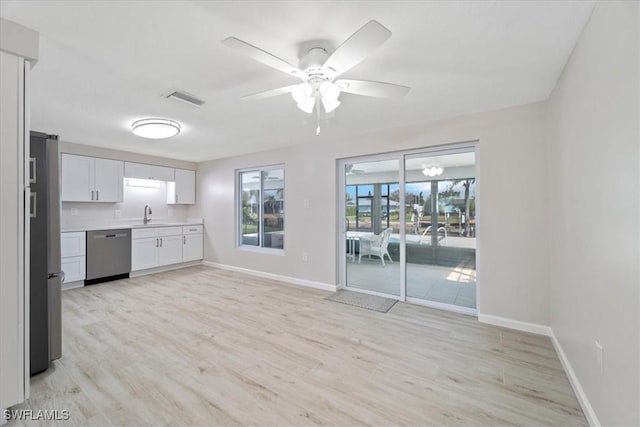 kitchen featuring baseboards, appliances with stainless steel finishes, light countertops, light wood-type flooring, and white cabinetry