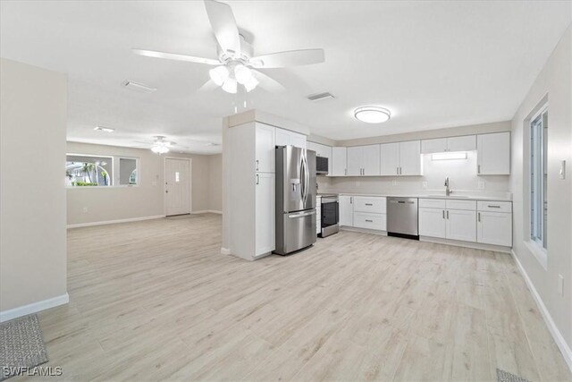 kitchen featuring stainless steel appliances, sink, white cabinets, and light wood-type flooring