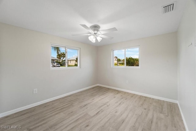 spare room featuring a ceiling fan, light wood-type flooring, visible vents, and baseboards