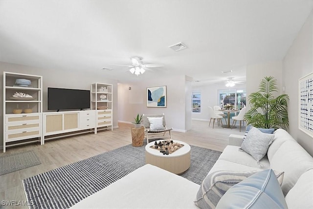 living room with a ceiling fan, baseboards, visible vents, and wood finished floors