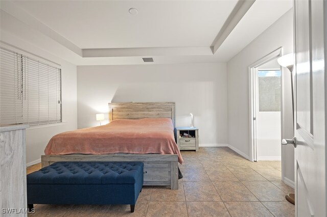 tiled bedroom featuring a tray ceiling