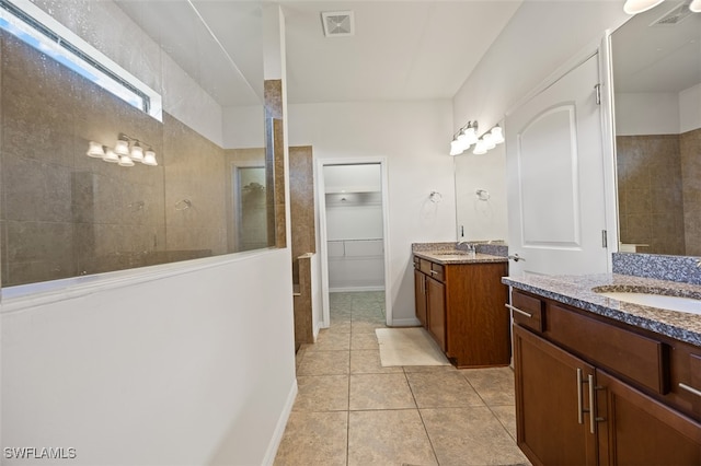 bathroom with tile patterned floors, vanity, and a tile shower