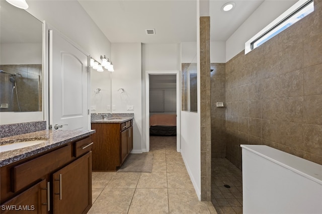 bathroom with tile patterned floors, vanity, and a tile shower