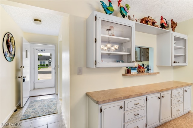 kitchen with white cabinetry, a textured ceiling, and light tile patterned floors