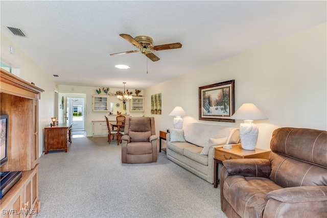 living room featuring a textured ceiling, light colored carpet, and ceiling fan with notable chandelier