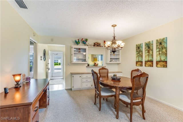 carpeted dining room featuring a notable chandelier and a textured ceiling