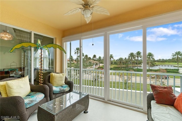 sunroom with ceiling fan and a water view