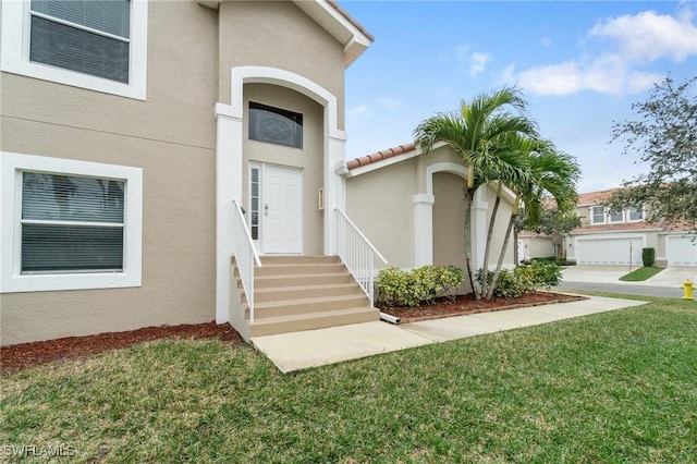 view of exterior entry with a garage and a yard