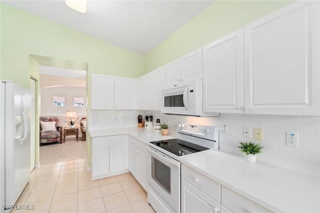 kitchen with white appliances, white cabinets, and light tile patterned flooring