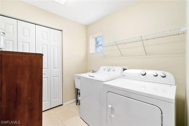 laundry room with independent washer and dryer and light tile patterned floors