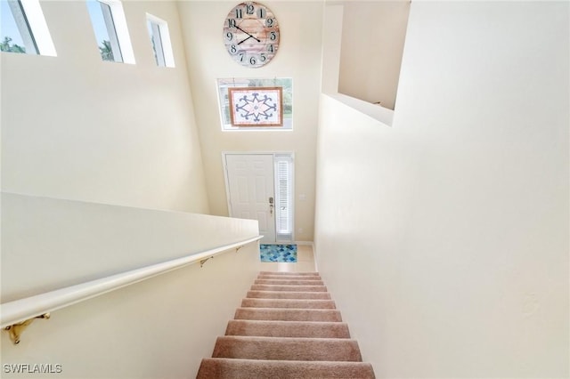 stairway featuring a towering ceiling