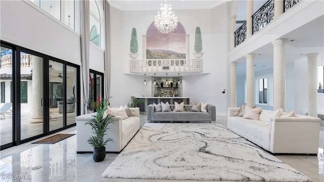 living room with ornate columns, a high ceiling, and an inviting chandelier