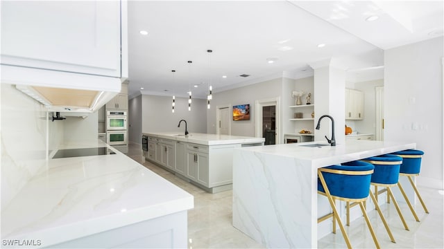 kitchen with a spacious island, light stone countertops, sink, and pendant lighting