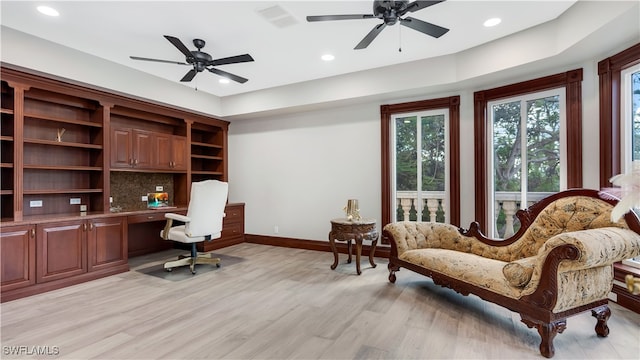 office area featuring built in desk, ceiling fan, and light wood-type flooring