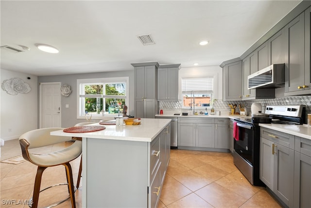 kitchen with stainless steel electric stove, a healthy amount of sunlight, backsplash, and a kitchen island