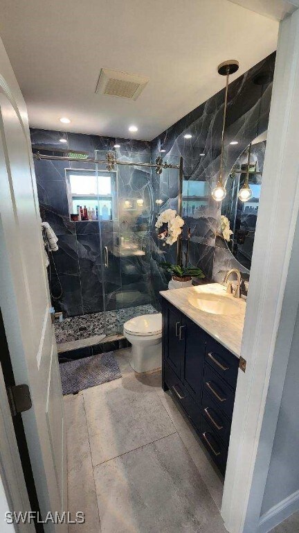 bathroom featuring tile walls, vanity, toilet, and an enclosed shower