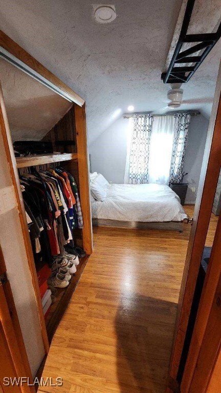 bedroom with hardwood / wood-style floors, vaulted ceiling, and a textured ceiling