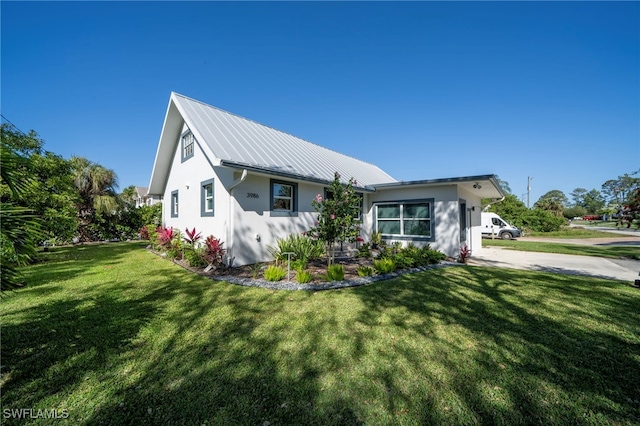 view of front of property featuring a front yard, metal roof, and stucco siding