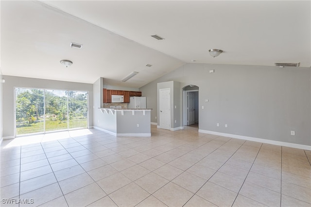 unfurnished living room featuring light tile patterned floors and vaulted ceiling