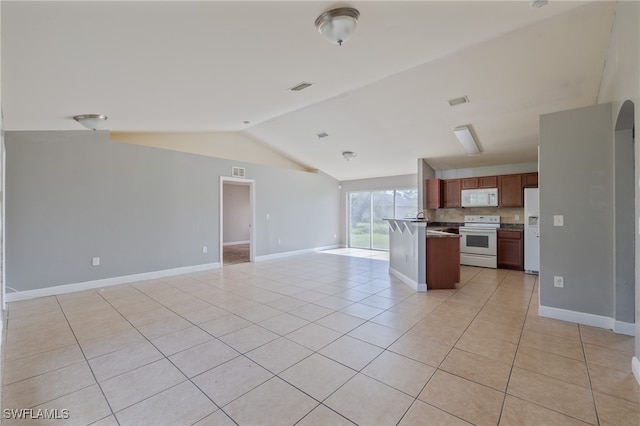 kitchen featuring lofted ceiling, decorative backsplash, a center island, light tile patterned floors, and white appliances