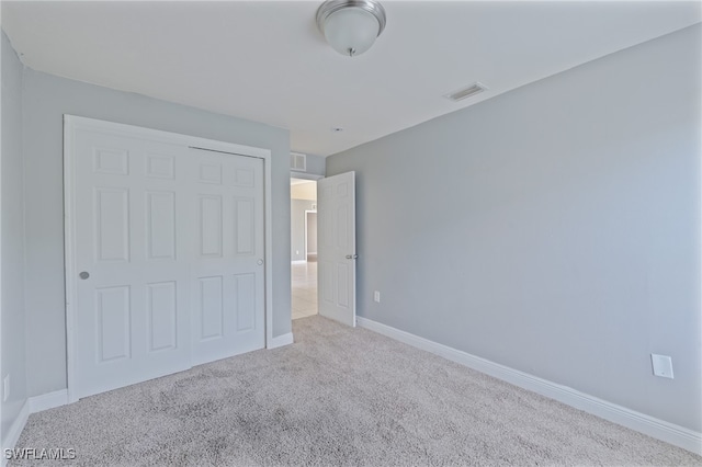 unfurnished bedroom featuring light carpet and a closet