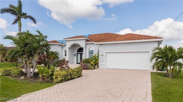 mediterranean / spanish home with a front yard and a garage