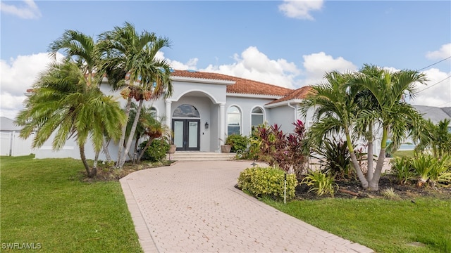 mediterranean / spanish-style home featuring a front yard and french doors