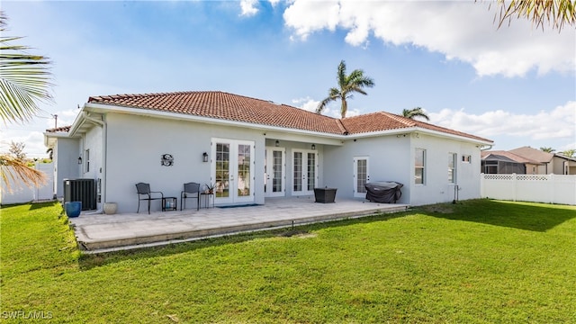 rear view of property featuring a lawn, a patio, central AC unit, and french doors