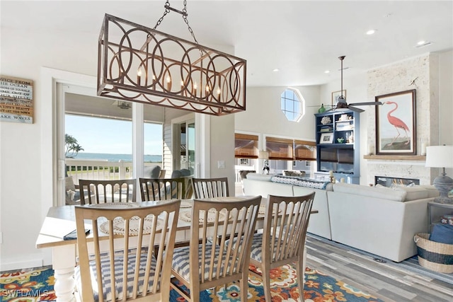 dining space featuring a fireplace, hardwood / wood-style flooring, and a water view