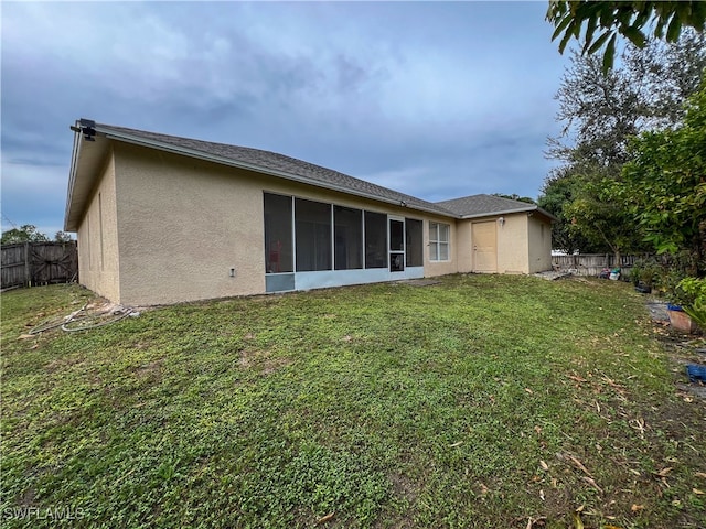 back of property with a yard and a sunroom