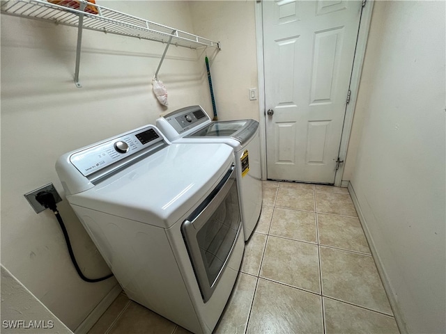 clothes washing area featuring washing machine and dryer and light tile patterned floors