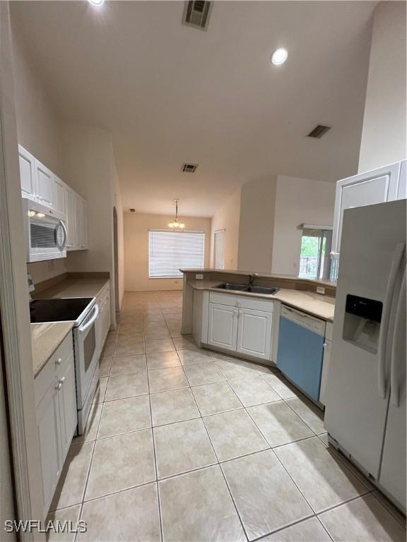 4895 Golfview Blvd, Lehigh Acres, FL 33973 - kitchen featuring white appliances, a chandelier, a peninsula, white cabinets, and light tile patterned floors