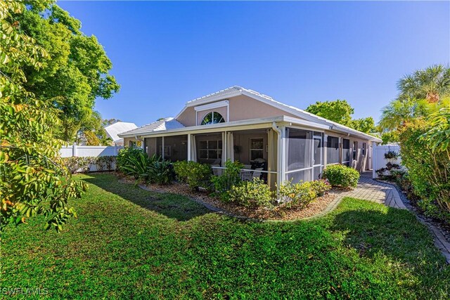 rear view of property with a sunroom and a yard