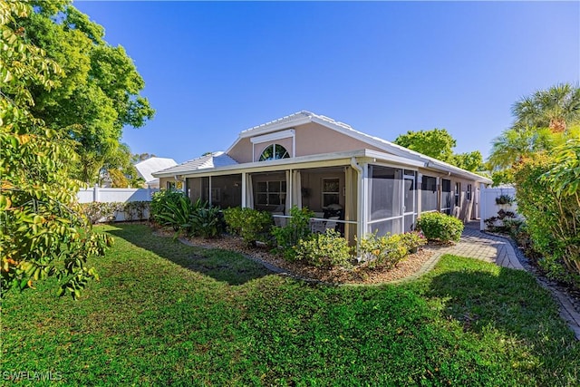 exterior space with a sunroom and a lawn