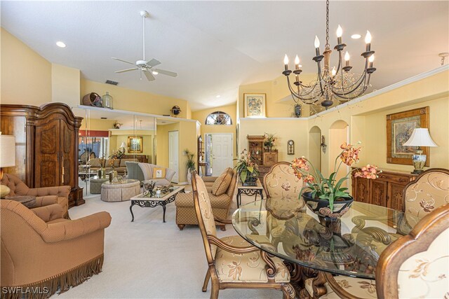 carpeted dining room featuring ceiling fan with notable chandelier and high vaulted ceiling