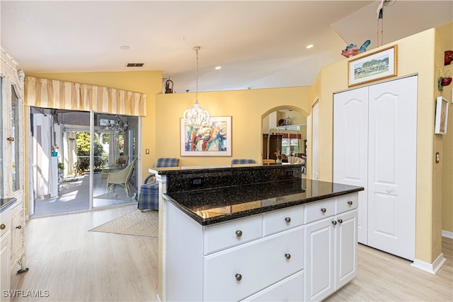 kitchen with dark stone counters, hanging light fixtures, light hardwood / wood-style flooring, lofted ceiling, and white cabinets