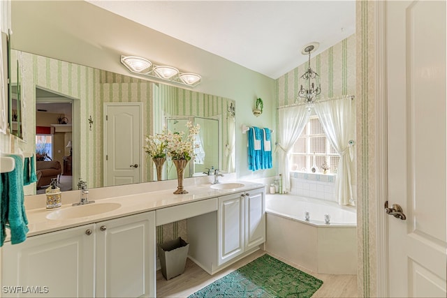 bathroom with tiled bath, vanity, hardwood / wood-style flooring, and an inviting chandelier