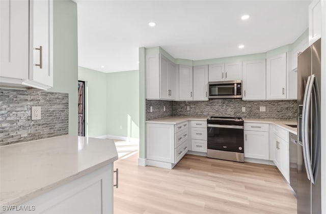 kitchen featuring appliances with stainless steel finishes, light stone countertops, decorative backsplash, white cabinets, and light hardwood / wood-style flooring