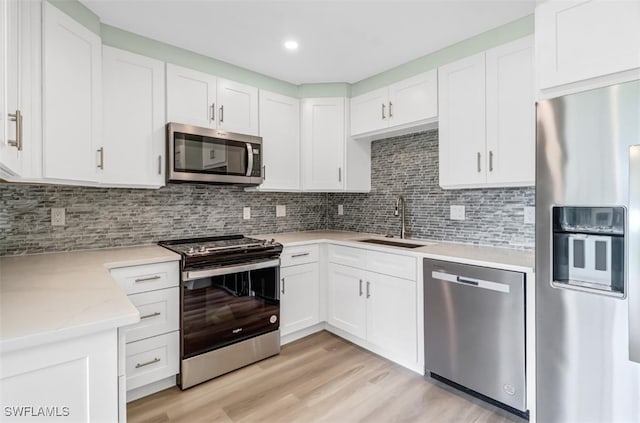 kitchen with white cabinetry, appliances with stainless steel finishes, sink, and light hardwood / wood-style flooring