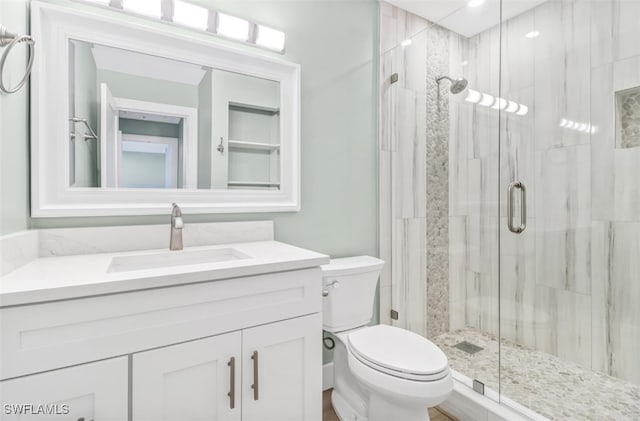 bathroom with vanity, toilet, and a shower with shower door