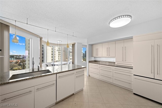 kitchen with a textured ceiling, white cabinetry, plenty of natural light, and white appliances