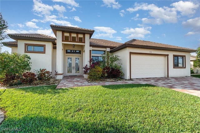 mediterranean / spanish home with an attached garage, decorative driveway, french doors, a front lawn, and stucco siding