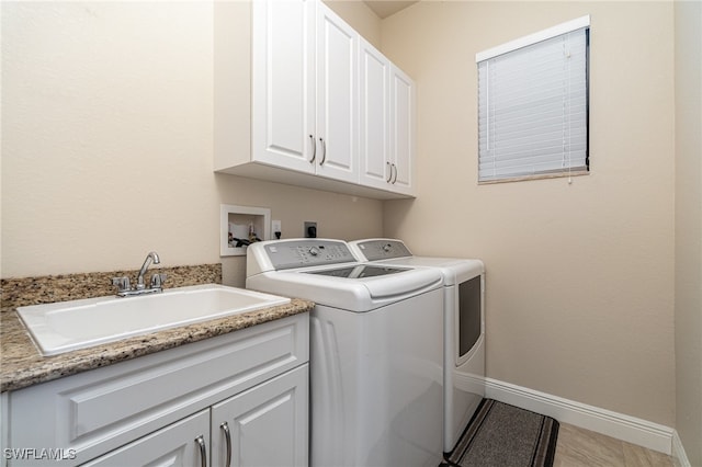 laundry area featuring baseboards, cabinet space, a sink, and washing machine and clothes dryer