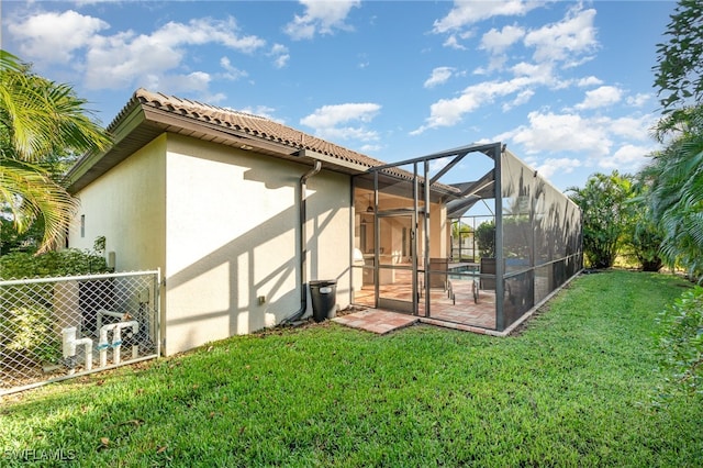 back of property with a lanai, a patio area, a yard, and stucco siding