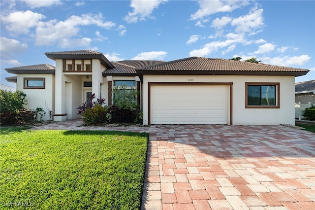 prairie-style house featuring a garage, a front yard, a tile roof, and stucco siding