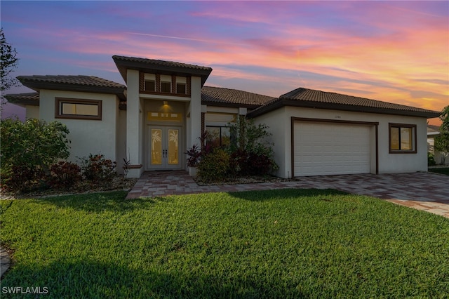 mediterranean / spanish house featuring an attached garage, stucco siding, decorative driveway, and french doors