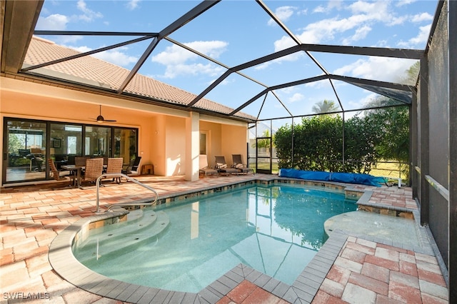 outdoor pool with a ceiling fan, glass enclosure, and a patio area