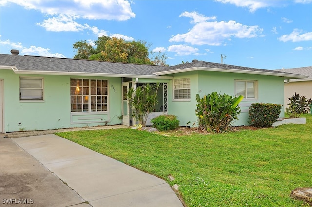 ranch-style home with a shingled roof, a front yard, and stucco siding