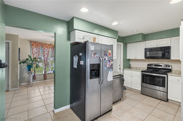 kitchen with white cabinets, stainless steel appliances, light tile patterned floors, and light stone countertops