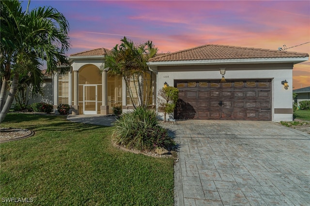 mediterranean / spanish home featuring a garage and a lawn